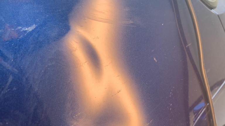 Delle und Kratzer im blauen Lack des vorderen rechten Kotflügels